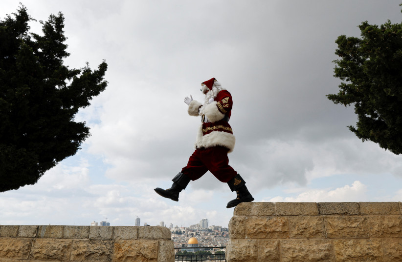  Issa Kassissieh wears a Santa Claus costume as he rides a camel during Christmas season on the Mount of Olives in Jerusalem. The Dome of the Rock is seen in the background. December 6, 2022. (photo credit: REUTERS/AMMAR AWAD)