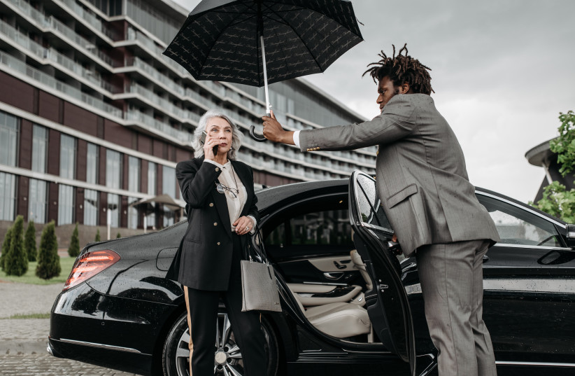  A man is seen holding an umbrella open for a woman (illustrative). (photo credit: PEXELS)