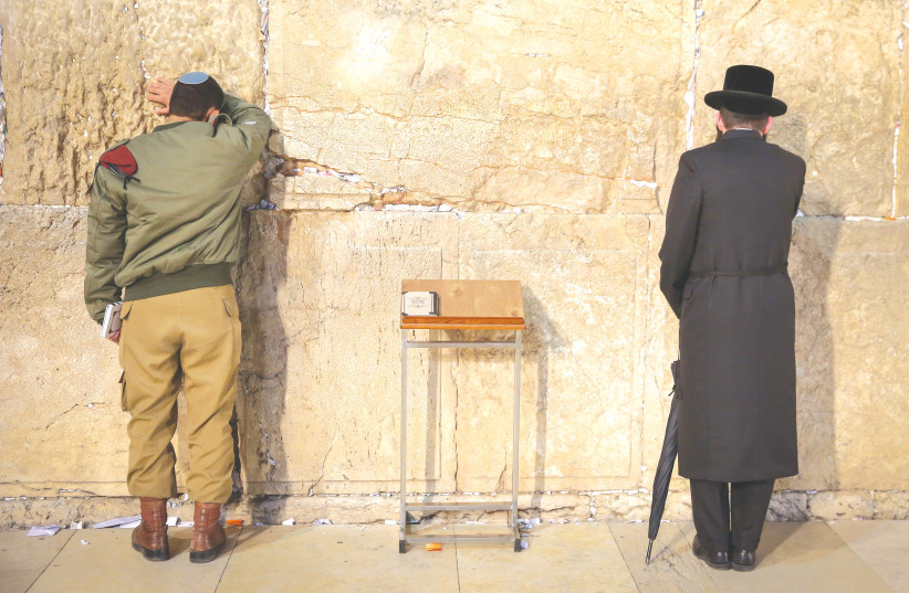 Un SOLDAT et un homme haredi prient au Mur Occidental. (crédit : David Cohen/Flash90)