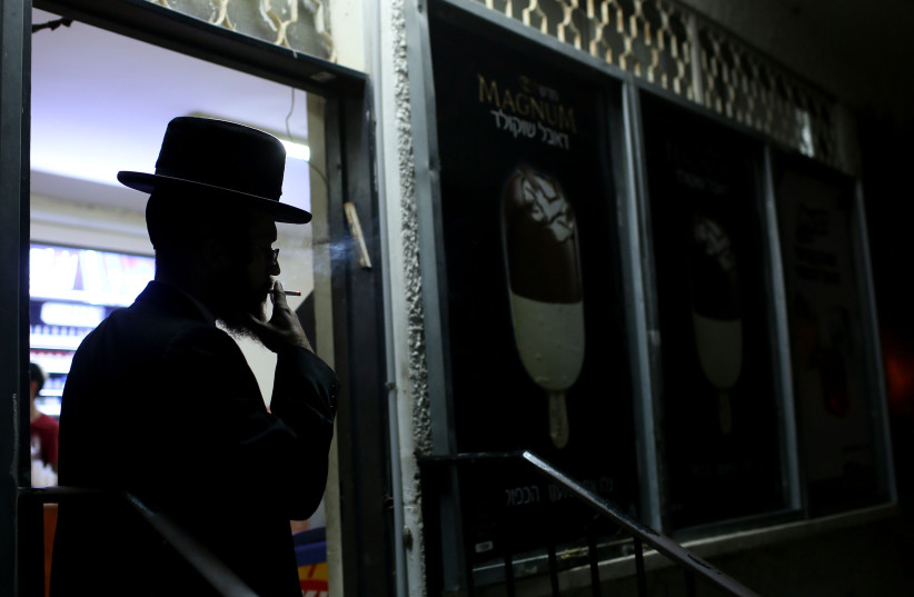  An ultra orthodox Jewish man smokes at the entrance of a store in the Kfar Habad. (photo credit: NATI SHOHAT/FLASH90)