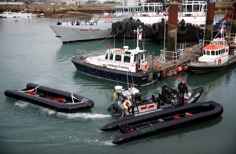  Members of Britain's Border Force tow into the Port of Dover an inflatable boat used by migrants who were rescued while crossing the English Channel, in Dover, Britain, April 14, 2022. (credit: PETER NICHOLLS/REUTERS)