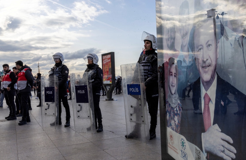 A banner of Turkish President Tayyip Erdogan is seen on the foreground as riot police secure the scene during protests against gender-based violence in Istanbul, Turkey November 27, 2022.  (photo credit: UMIT BEKTAS/REUTERS)