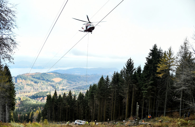  An Italian fire brigade helicopter prepares to lift the crashed cable car cabin, which left 14 people dead, after it collapsed on May 23, 2021, in Stresa, near Lake Maggiore, Italy November 8, 2021. (photo credit: REUTERS/FLAVIO LO SCALZO)