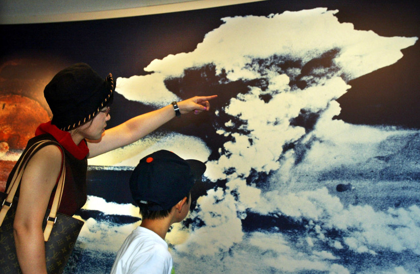  A mother and son look at a picture of the mushroom cloud atomic bomb blast as they visit Hiroshima Peace Memorial Museum in Hiroshima August 5, 2002, the eve of the 57th anniversary of the bombing of the city. (credit: REUTERS/FILE PHOTO)