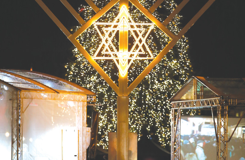  A GIANT MENORAH stands in front of a Christmas tree at the Brandenburg Gate in Berlin, 2014. (photo credit: Fabrizio Bensch/Reuters)