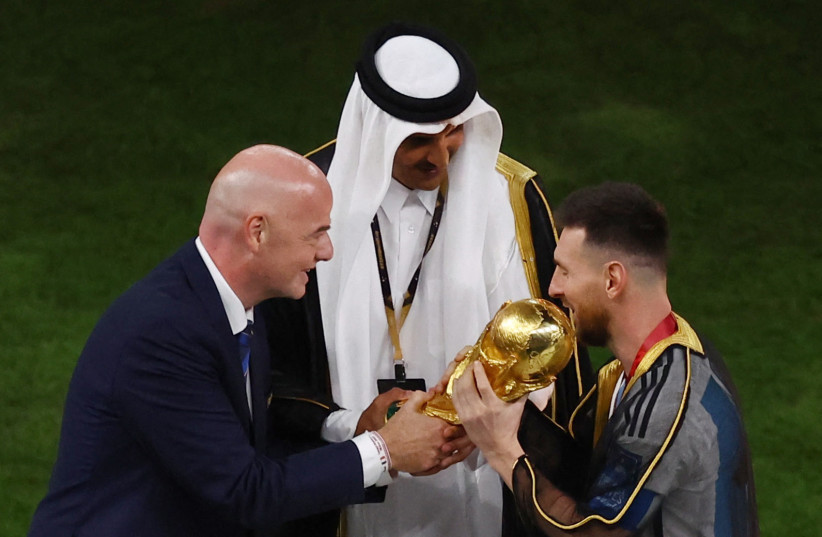  FIFA president Gianni Infantino hands the World Cup trophy to Argentina's Lionel Messi as Emir of Qatar Sheikh Tamim bin Hamad Al Thani watches, December 18, 2022 (credit: REUTERS/PAUL CHILDS)