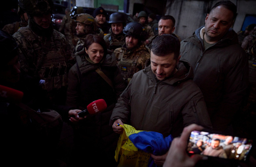  Ukraine's President Volodymyr Zelenskiy holds a national flag as he visits a position of Ukrainian service members in the frontline town of Bakhmut, amid Russia's attack on Ukraine, in Donetsk region, Ukraine December 20, 2022. (credit: Ukrainian Presidential Press Service/Handout via REUTERS)