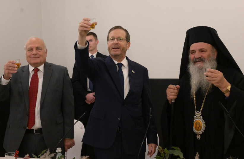  Israeli President Isaac Herzog (center) and Tel Aviv Mayor Ron Huldai (left) celebrate with members of the Jaffa Christian community (December 21, 2022). (credit: AMOS BEN-GERSHOM/GPO)