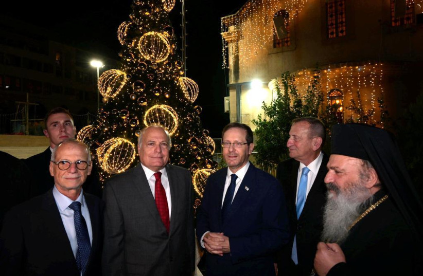  Israeli President Isaac Herzog, retired Supreme Court Justice George Kara and Tel Aviv Mayor Ron Huldai lit the Christmas tree with members of the Jaffa Christian community (December 21, 2022). (photo credit: AMOS BEN GERSHOM/GPO)