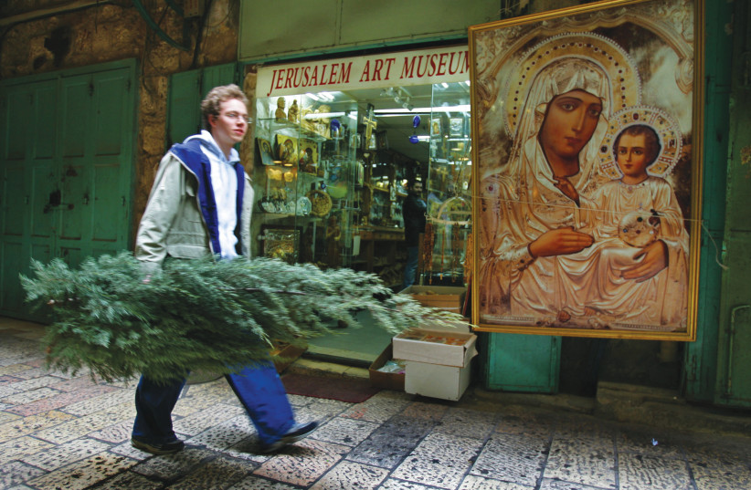  CARRYING A Christmas tree past a Christian Quarter souvenir shop.  (credit: David Silverman/Getty Images)