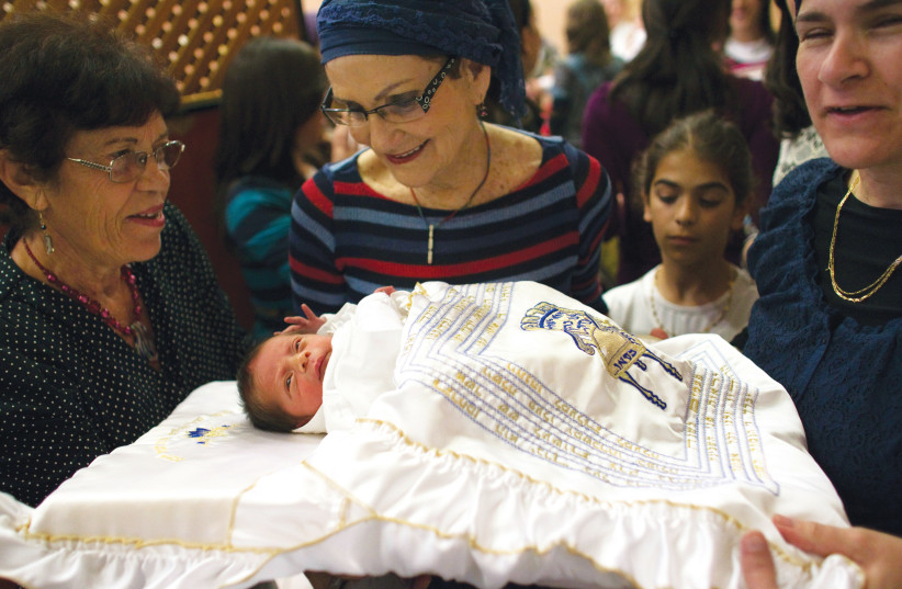  RELATIVES SURROUND a baby after circumcision, in Jerusalem. The book explores different customs regarding aspects of circumcision. (photo credit: REUTERS/Ronen Zvulun)
