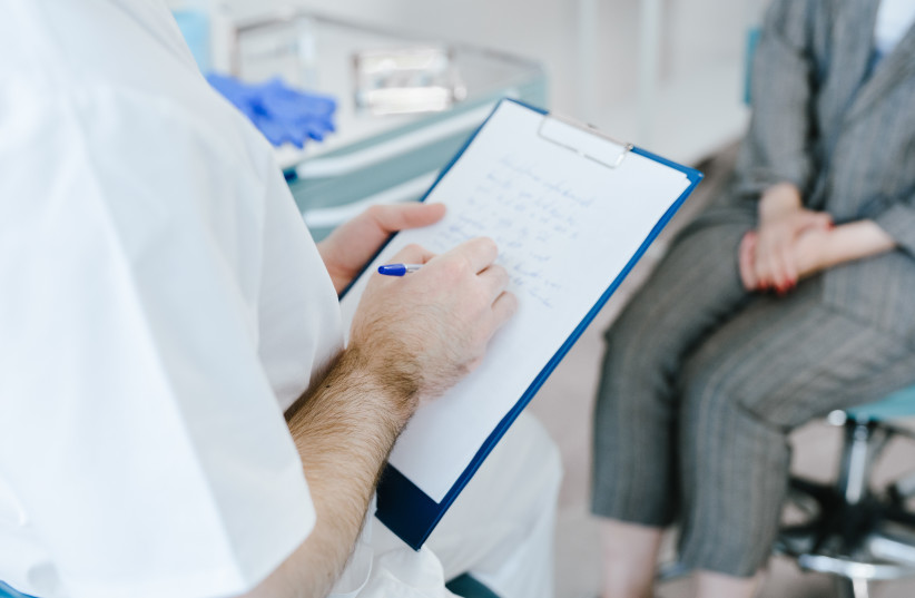  Doctor writing notes during a session with a patient. (photo credit: PEXELS)