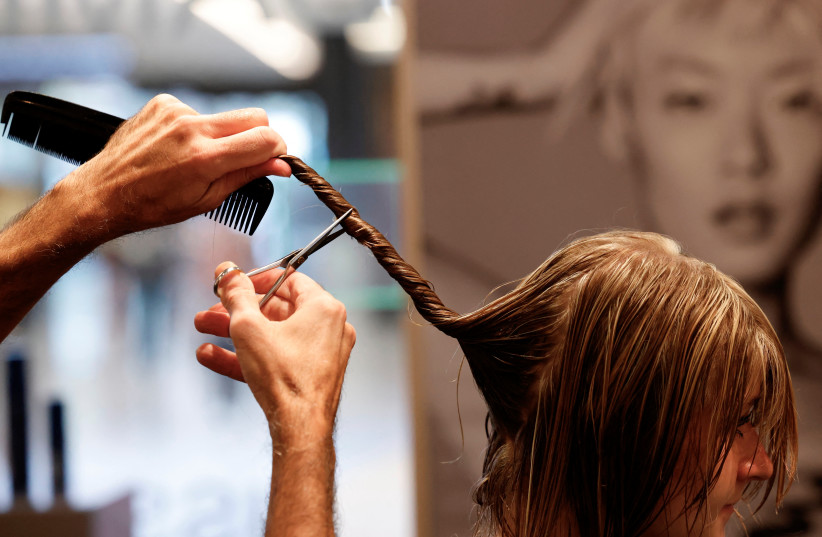  Belgian hairdresser at hair salon L'Atelier Chedly Boussigua cuts a customer's hair, which will be collected by the association Dung Dung that transforms hair into tiles used to absorb polluting chemical substances in water, in Brussels, Belgium November 4, 2022. (photo credit: YVES HERMAN/REUTERS)