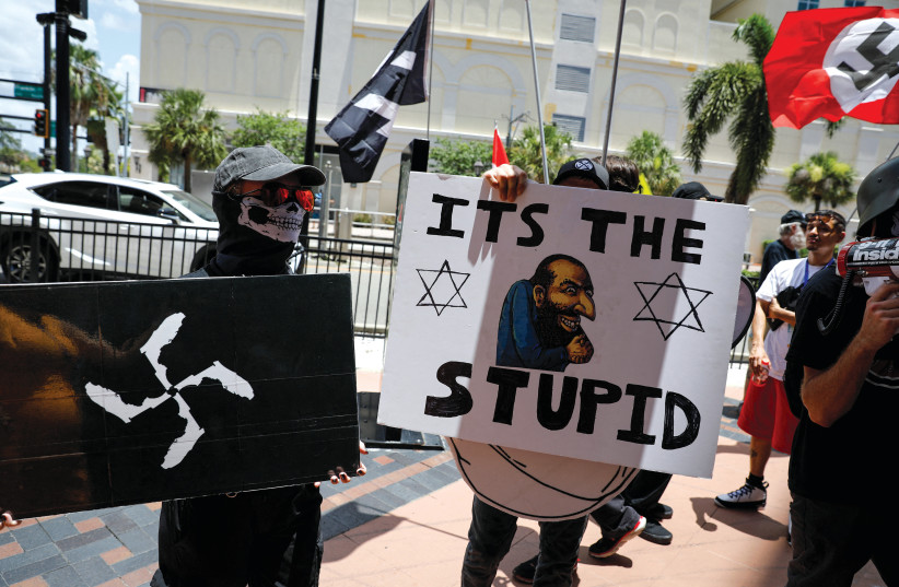  Demonstrators hold antisemitic symbols and signs as they protest outside the Tampa Convention Center, where Turning Point USA’s Student Action Summit was being held, in Tampa, Florida on July 23, 2022.  (photo credit: MARCO BELLO/REUTERS)