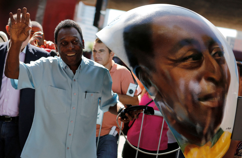  Brazilian soccer legend Pele waves next to a public telephone booth with an image of his face painted by Brazilian artist Sipros after he autographed it, during the Call Parade art exhibition in Sao Paulo, Brazil, May 8, 2014. (photo credit: NACHOS DOCE / REUTERS)
