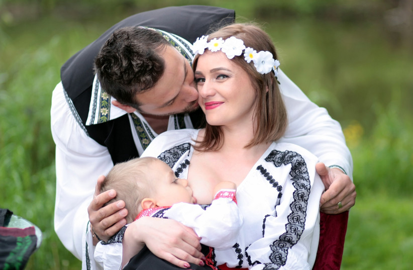  A woman breastfeeds her baby while posing for a photo with her partner.  (credit: CREATIVE COMMONS)