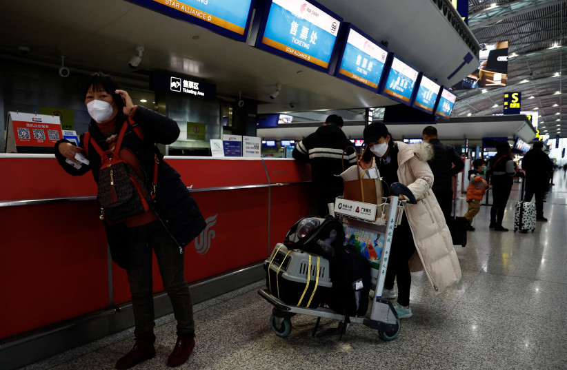  Travellers stand at a ticketing counter at Chengdu Shuangliu International Airport amid a wave of the coronavirus disease (COVID-19) infections, in Chengdu, Sichuan province, China December 30, 2022.  (photo credit: TINGSHU WANG/REUTERS)