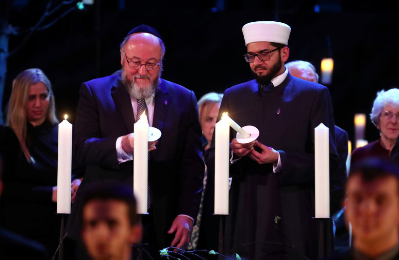  Chief Rabbi Ephraim Mirvis (L) lights a candle during the UK Holocaust Memorial Day Commemorative Ceremony in Westminster in London, Britain January 27, 2020. (credit: CHRIS JACKSON/POOL VIA REUTERS)