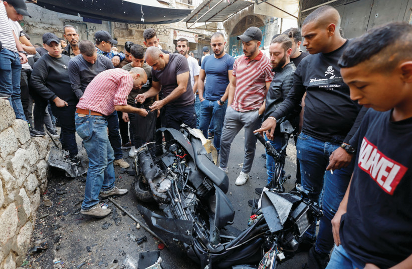  NABLUS RESIDENTS inspect a damaged motorcycle at the scene where Lions’ Den member Tamer Kilani was killed in an explosion, in October. (credit: REUTERS/RANEEN SAWAFTA)
