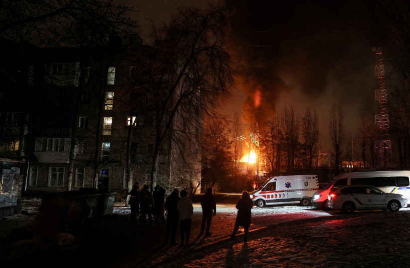 Local residents gather near a residential building as a critical power infrastructure object burns after a Russian drone attack, amid Russia's attack on Ukraine, in Kyiv, Ukraine, December 19, 2022. (photo credit: REUTERS/GLEB GARANICH/FILE PHOTO)