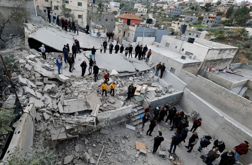  People gather near the remains of the house of Palestinian terrorist Ahmad Aabed after Israeli forces demolish it, in Kafr Dan village, near Jenin, in the West Bank, January 2, 2023. (photo credit: REUTERS/RANEEN SAWAFTA)
