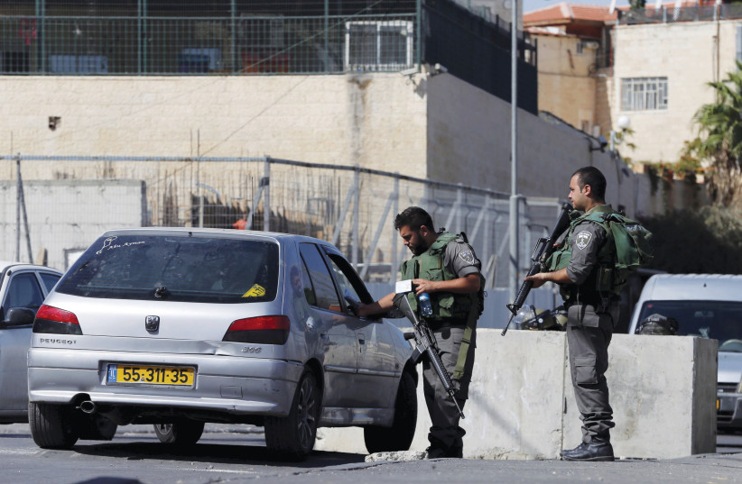  ISRAELI BORDER policemen check a car at a roadblock in east Jerusalem last year. (credit: AMMAR AWAD/REUTERS)