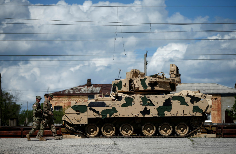 US servicemen walk past a Bradley infantry fighting vehicle as they arrive for the joint U.S.-Georgian exercise Noble Partner 2016 in Vaziani, Georgia, May 5, 2016 (photo credit: REUTERS/DAVID MDZINARISHVILI)