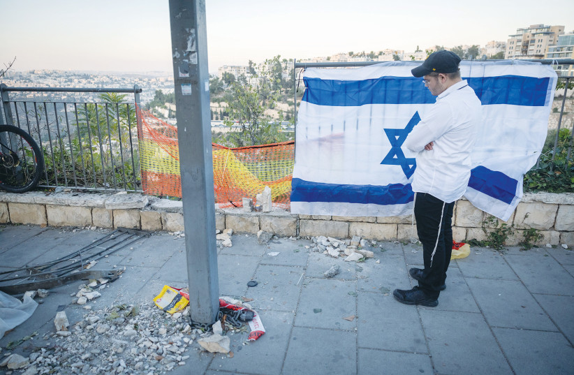  AN ISRAELI flag hangs as a religious man ponders at the scene of a terror attack at the entrance to Jerusalem, on November 23. (photo credit: YONATAN SINDEL/FLASH90)