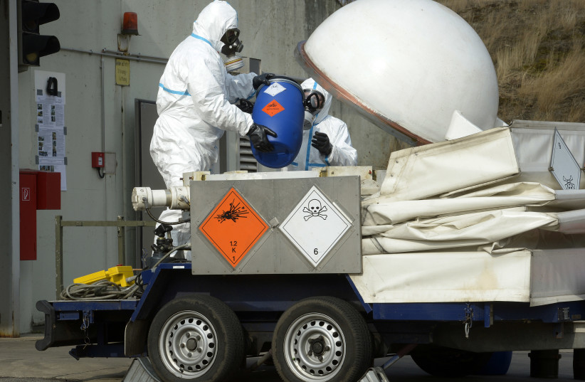  Workers dressed in protective clothing, handle a dummy chemical World War Two weapon during a media demonstration at the Society for the Disposal of Chemical Weapons and Ordnance (GEKA) in Munster, March 5, 2014. (credit: FABIAN BIMMER / REUTERS)