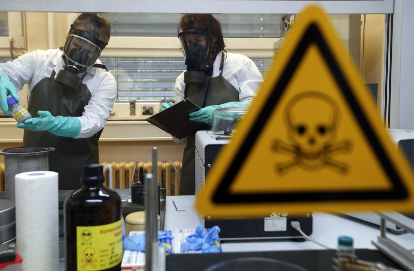  Employees of the Research Institute for Protective Technologies, Nuclear, Biological and Chemical Protection (WIS) inspect a dummy sample which is contaminated with a substance similar to the chemical weapon Sarin, during a demonstration in Munster October 15, 2013. (photo credit: Fabrizio Bensch/Reuters)