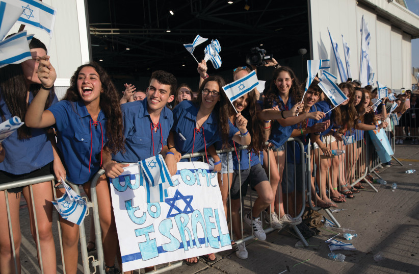  YOUNG ISRAELIS welcome new immigrants at Ben-Gurion Airport. Most Israelis, whether secular or religious, believe the country must have historical and spiritual continuity, says the writer. (photo credit: NATI SHOHAT/FLASH90)