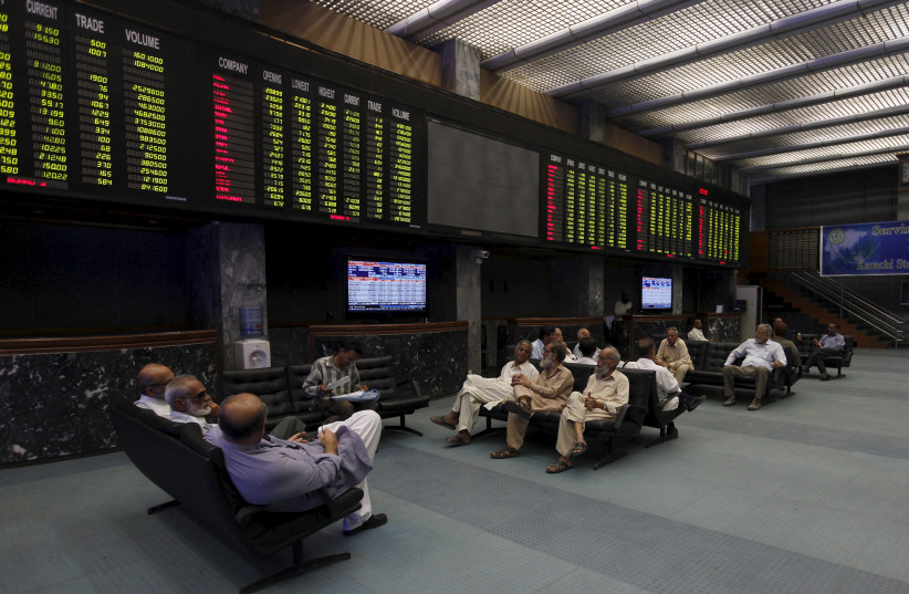 Investors and brokers sit on couches under the electronic board displaying share market prices during a trading session in the halls of Karachi Stock Exchange, Pakistan, August 25, 2015. (credit: REUTERS/AKHTAR SOOMRO)