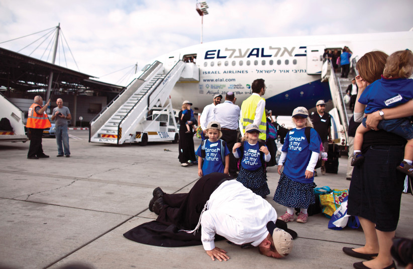  A Jewish immigrant from North America kisses the ground as his family looks on after disembarking from an El Al plane chartered by Nefesh B’Nefesh at Ben-Gurion Airport. (photo credit: NIR ELIAS/REUTERS)