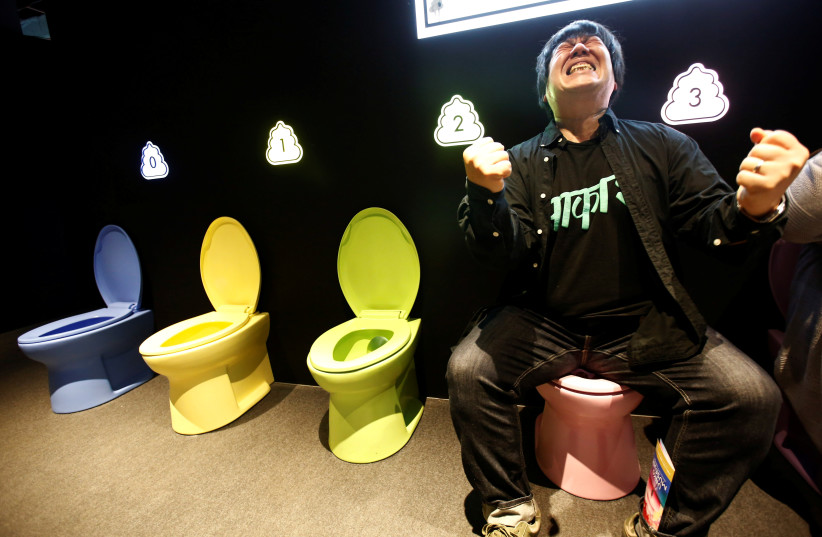  A visitor pretends to defecate on a display toilet at the the Unko (''poop'' in Japanese) museum in Yokohama, Japan, April 17, 2019 (credit: REUTERS/KIM KYUNG-HOON)