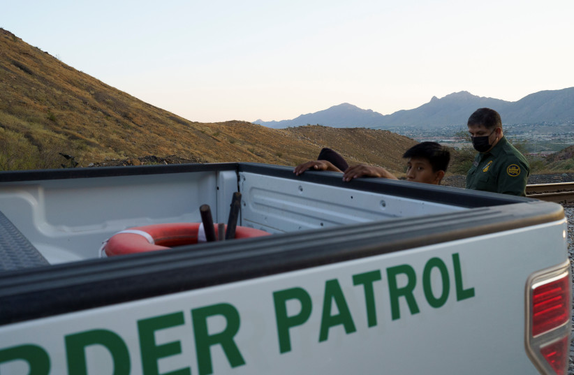 Guatemalan men are searched by US Border Patrol agents after trying to cross the border from Mexico into Sunland Park, NM, US, September 17, 2021. (photo credit: PAUL RATJE/REUTERS)