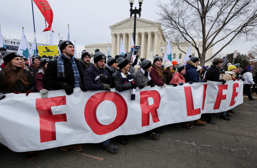  Anti-abortion activists hold a banner as they walk in front of the U.S. Supreme Court building during the annual "March for Life", in Washington, U.S., January 21, 2022. (photo credit: REUTERS/JIM BOURG)