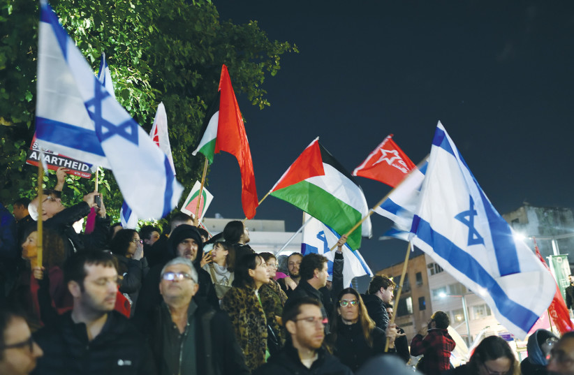 PALESTINIAN AND Israeli flags are waved at a demonstration protesting against the policy of the new Netanyahu government, in Tel Aviv, earlier this month.  (credit: GILI YAARI/FLASH90)
