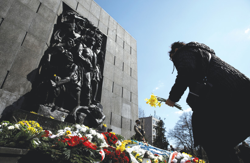  A WOMAN lays daffodils during the commemoration of the anniversary of the Warsaw Ghetto Uprising, in front of the Warsaw Ghetto monument in Warsaw, in 2021.  (credit: KACPER PEMPEL/REUTERS)