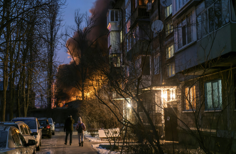  Local residents walk near a residential building as a critical power infrastructure object burns after a Russian drone attack, amid Russia's attack on Ukraine, in Kyiv, Ukraine December 19, 2022.  (credit: REUTERS/VLADYSLAV MUSIIENKO)