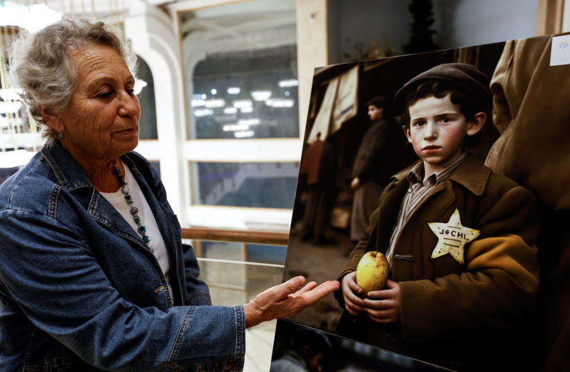  A visitor gestures as she attends the opening of an exhibition which displays images created using the memories of Holocaust survivors and Midjourney, an artificial intelligence program that creates images from text. (credit: REUTERS/AMIR COHEN)