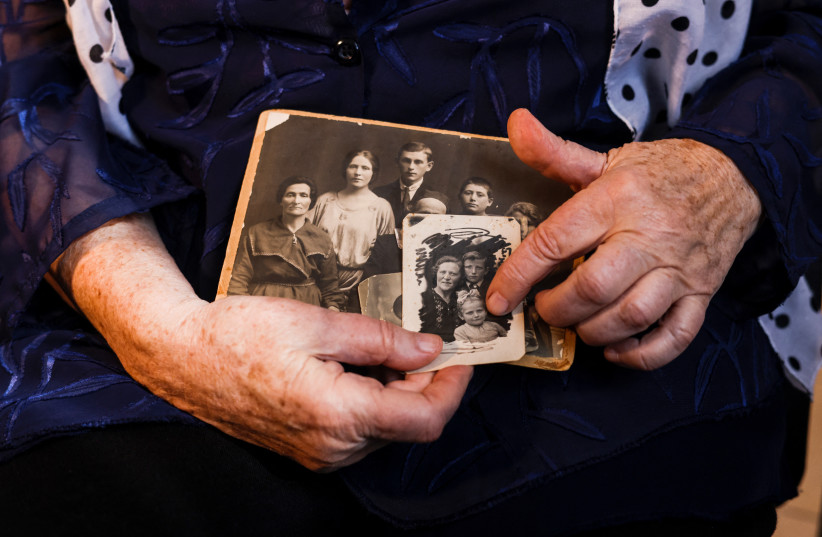  Holocaust survivor Klara Gurevich, 86, who was born in Ukraine holds family photographs which were used to create avatars that together with a memory were transformed into images using Midjourney, an artificial intelligence program that creates images from text. (credit: REUTERS/AMIR COHEN)