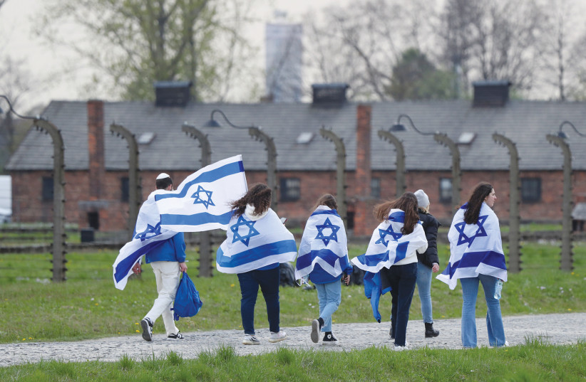  MARCHERS WRAPPED in Israeli flags attend the annual March of the Living at the former Auschwitz II-Birkenau death camp, near Oswiecim, Poland last year. (photo credit: REUTERS/KACPER PEMPEL)