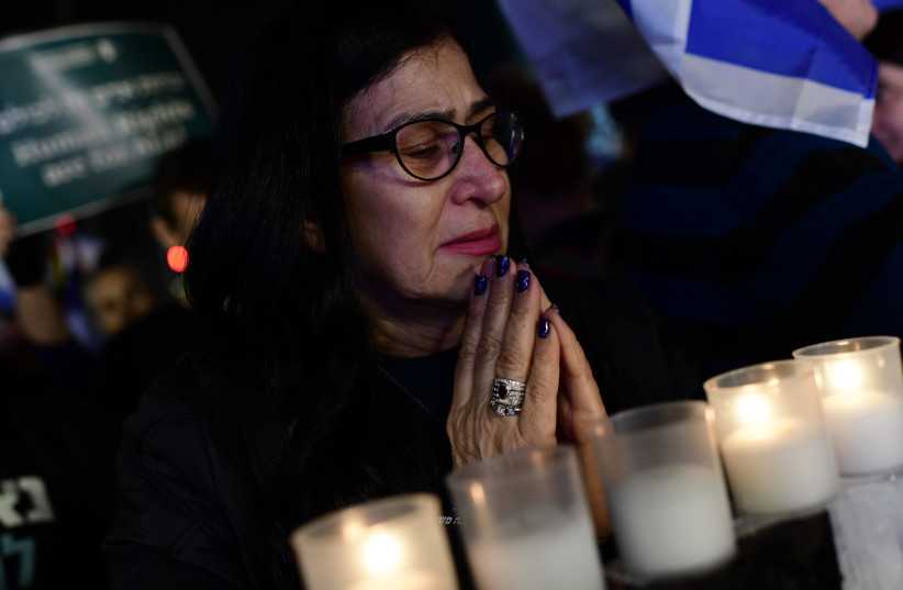  People light candles in memory of the 7 victims of last night terror attack during a protest against the proposed changes to the legal system, in Tel Aviv, on January 28, 2023. (credit: TOMER NEUBERG/FLASH90)