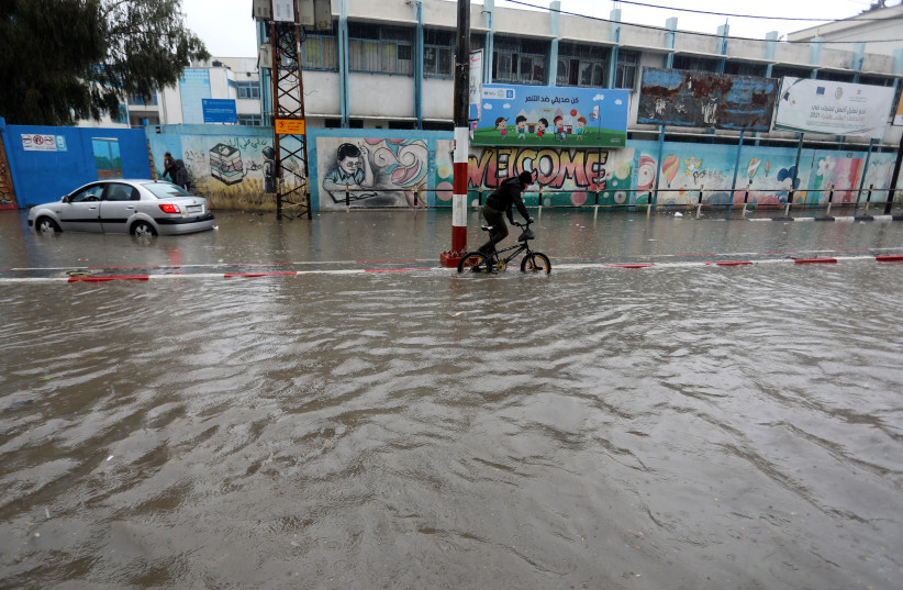   Palestinians seen at a road flooded with rainwater following heavy rains, in Rafah, in the southern Gaza Strip on January 16, 2022. (credit: ABED RAHIM KHATIB/FLASH90)