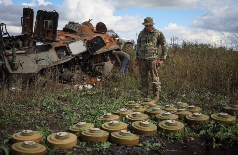  Ukrainian serviceman examines anti tanks mines near a destroyed Russian Armoured Personnel Carrier (APC), as Russia's attack on Ukraine continues, near the town of Izium, recently liberated by Ukrainian Armed Forces, in Kharkiv region, Ukraine September 24, 2022. (photo credit: REUTERS/GLEB GARANICH)