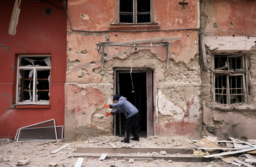  Zoya Mykolaivna, 84, removes debris in front of her apartment at a residential building damaged by a Russian military strike, amid Russia's invasion of Ukraine, in Kherson, Ukraine January 25, 2023. (photo credit: NACHO DOCE/REUTERS)