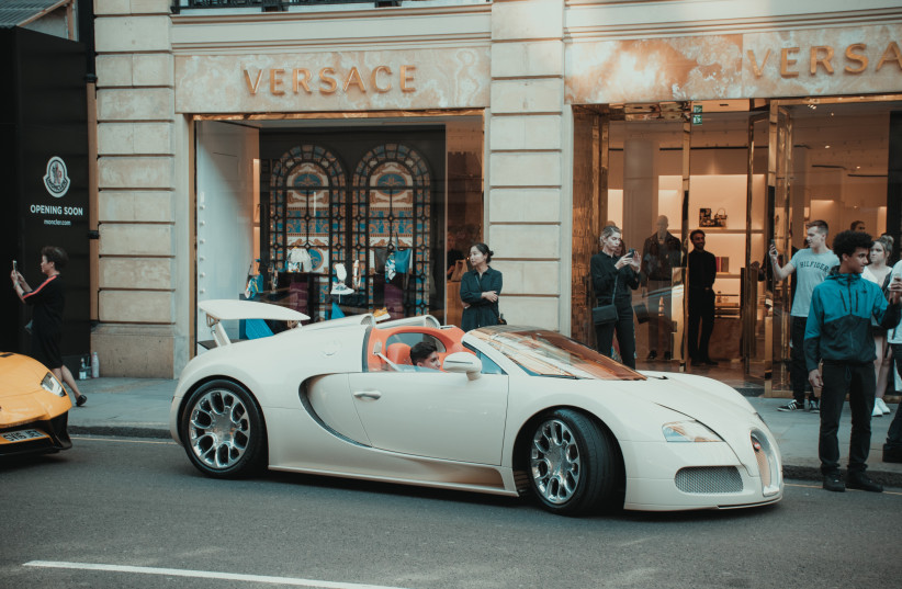 A luxury car in front of a designer store. (photo credit: UNSPLASH)