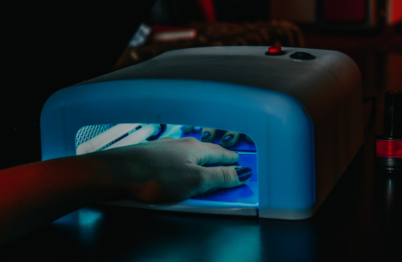 Is there a safer way to paint your nails besides gel manicures? (Illustrative image of woman drying nails under UV light) (photo credit: PEXELS)