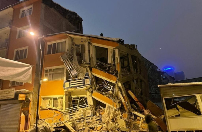 A man walks past by a collapsed building after an earthquake in Malatya, Turkey, February 6, 2023. (credit: DEPO PHOTOS VIA REUTERS)