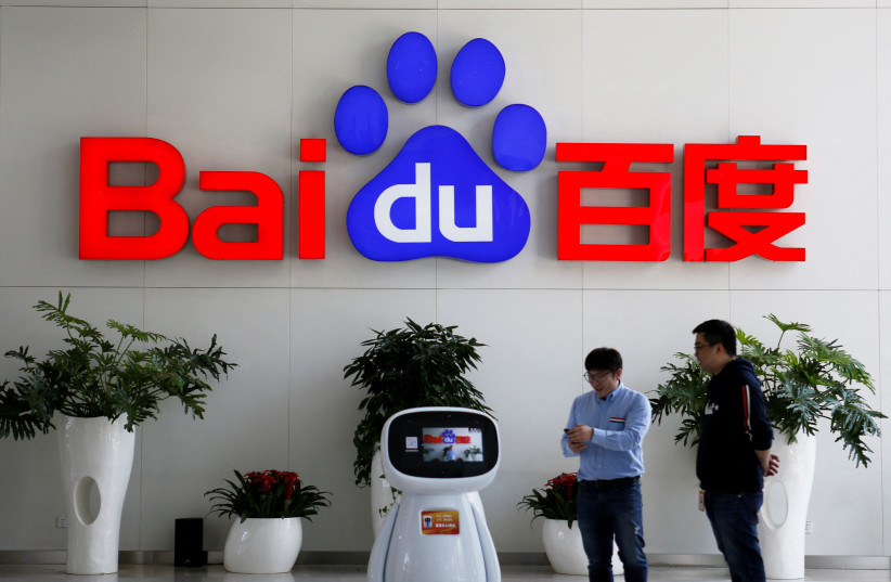  Men interact with a Baidu AI robot near the company logo at its headquarters in Beijing, China April 23, 2021.  (photo credit: REUTERS/FLORENCE LO)